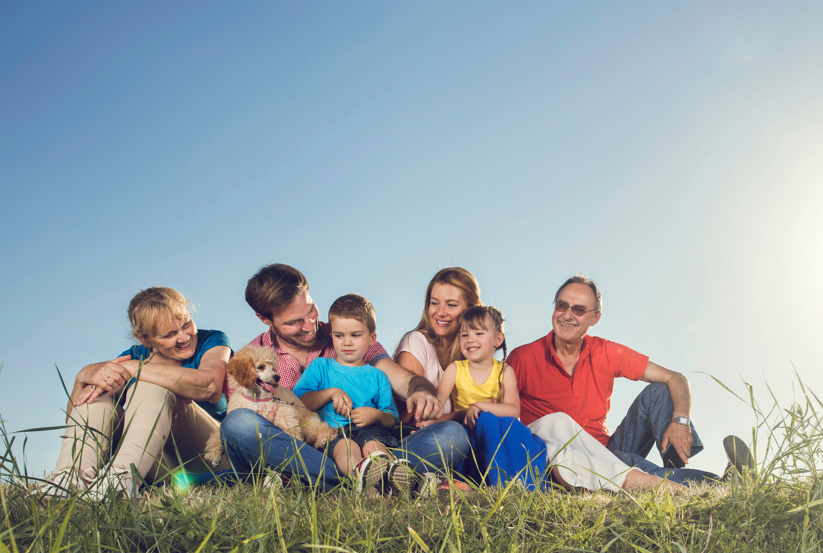 Family sitting together in the grass on a sunny day